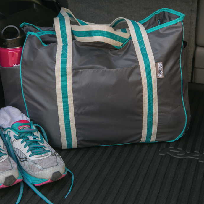 ChicoBag Smoked Pearl colored nomad reusable tote in the back of a car filled with gym clothes 